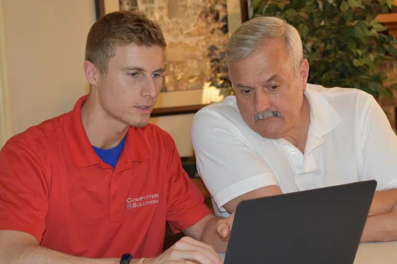 Preston and a man looking together at an open laptop.