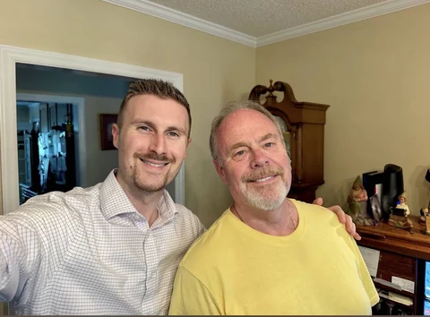 Preston beside a man wearing a yellow shirt during a home visit.