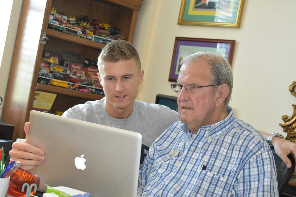Preston and a man reviewing an open Apple laptop