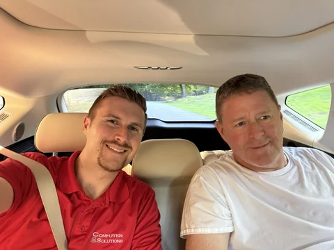 Preston and a man seated together inside a car.