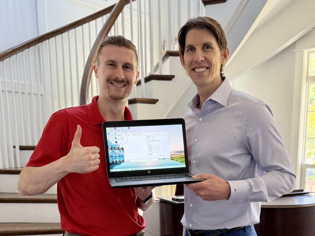 Preston in a red polo beside a man holding a laptop